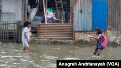 Anak-anak sedang bermain saat banjir rob melanda kawasan Kecamatan Medan Belawan, Kota Medan, Sumatra Utara. Jumat 19 Mei 2023