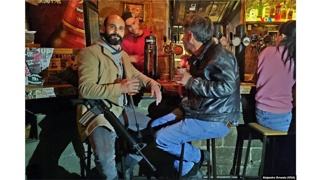 Un reservista en activo posa en un bar portando su arma reglamentaria. Una escena común en Jerusalén.