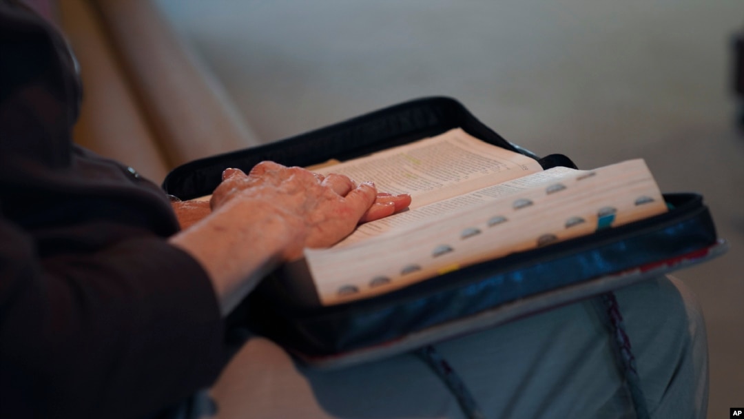 FILE - Seorang umat di First Baptist Church, Mt. Vernon, Illinois, meletakkan tangannya di atas Alkitab saat mengikuti khotbah Minggu, 10 September 2023. (AP/Jessie Wardarski )