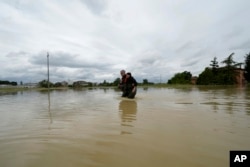 FILE - Sepasang suami istri mengarungi jalanan di Lugo, Italia, yang tergenang banjir, 18 Mei 2023. (AP/Luca Bruno)