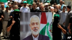 Anggota Hamas memegang poster kepala politik Hamas Ismail Haniyeh yang terbunuh dalam aksi protes di kamp pengungsi Palestina al-Bass, di kota pelabuhan selatan Tyre, Lebanon, Rabu, 31 Juli 2024. (Mohammed Zaatari/AP)