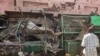 FILE - People walk past a medical center building riddled with bullet holes at the Souk Sitta (Market Six) in the south of Khartoum, Sudan, on June 1, 2023.