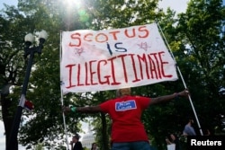 Seorang aktivis hak aborsi memegang papan bertuliskan "SCOTUS tidak sah" di dekat gedung Capitol AS dan Mahkamah Agung AS di Washington, AS, 24 Juni 2023. (REUTERS/Elizabeth Frantz).