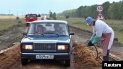 FILE - A veterinarian hoses a car with disinfectant to prevent the spread of anthrax near the village of Druzhba, Russia, Aug. 29, 2012. Five countries in Africa are in the middle of outbreaks of the anthrax disease, with 20 deaths reported so far in 2023.