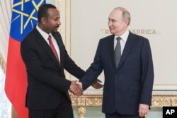 Russian President Vladimir Putin, right, and Ethiopian Prime Minister Abiy Ahmed shake hands during their meeting on the eve of the Russia-Africa Summit in St. Petersburg, July 26, 2023