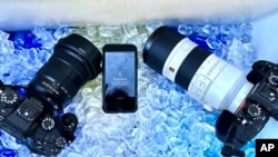 The cameras and cell phone of Associated Press photographer Ross Franklin sit on ice after the devices stopped working after overheating, July 20, 2023, in Tempe, Ariz.