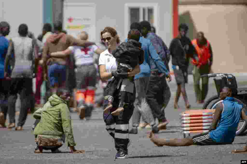 A member of the emergency services carries a child, part of a group of 175 migrant people who arrived on board a boat, at Restinga port on the Canary island of El Hierro, Spain.