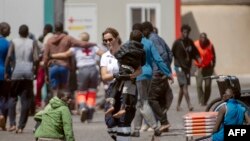 A member of the emergency services carries a child, part of a group of 175 migrant people who arrived on board a boat, at Restinga port on the Canary island of El Hierro, Spain.