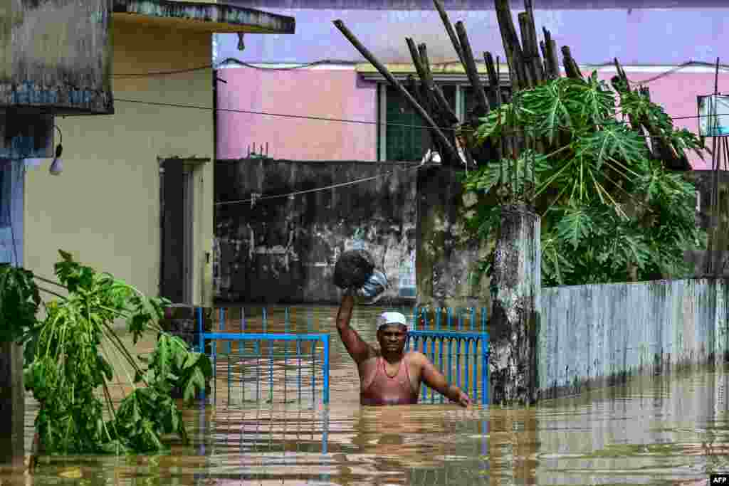 Seorang pria membawa barang-barangnya berjalan melewati banjir di kota Feni, di wilayah tenggara Bangladesh. (AFP)&nbsp;