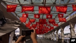 Mainland Chinese tourists take photographs as Chinese and Hong Kong flags are strung to mark the 26th anniversary of the city's handover from Britain to China in Hong Kong, on June 27, 2023. 