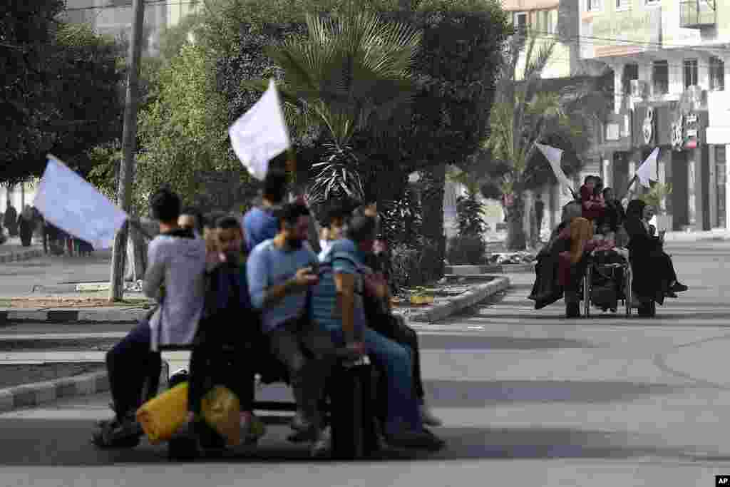 Палестинците на колички со магариња држат бели знамиња обидувајќи се да спречат да бидат застрелани, додека бегаат од градот Газа во населбата Ал-Римал, во центарот на градот Газа.