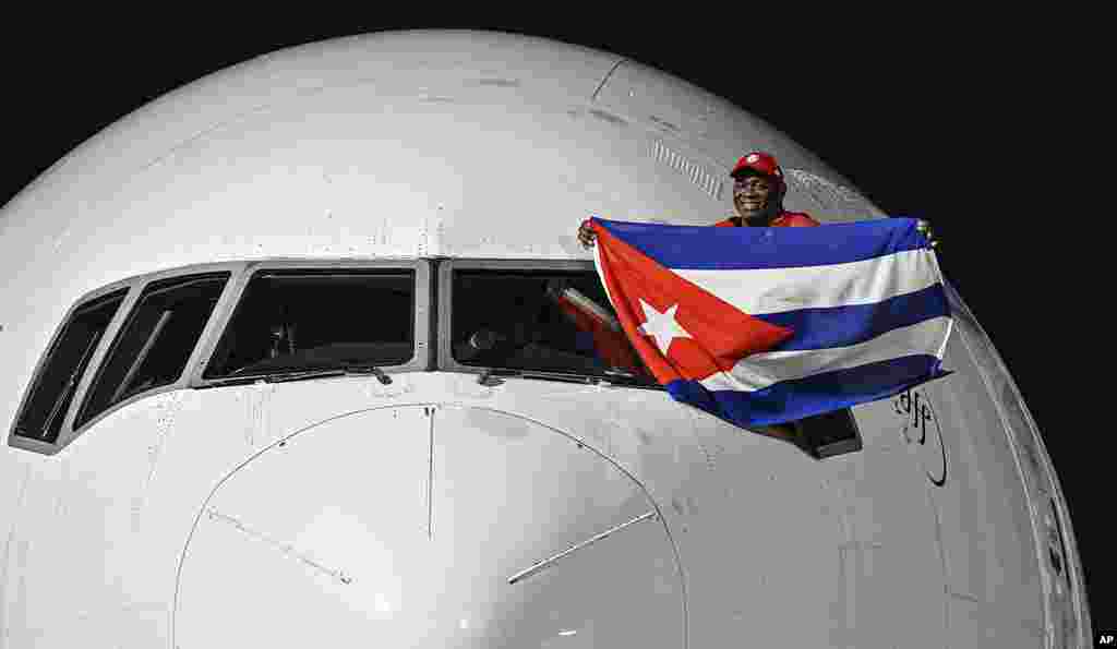 Cuban wrestler Mijain Lopez Nunez, a five-time Olympic champion, waves a Cuban flag from the pilot's window of a plane as he arrives at Jose Marti airport in Havana, Cuba, Aug. 12, 2024.