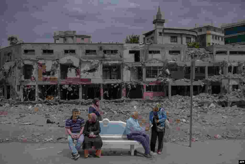 People wait at a bus stop in front of a destroyed building during the presidential runoff vote in the quake-hit city of Kahramanmaras, Turkey.