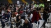 ARCHIVO - Migrantes venezolanos se sientan durante un día de entregas de Permiso de Protección Temporal (PPT) organizado por Migración Colombia en el Palacio de los Deportes en Bogotá, Colombia, 1 de septiembre de 2023.