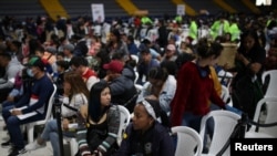ARCHIVO - Migrantes venezolanos se sientan durante un día de entregas de Permiso de Protección Temporal (PPT) organizado por Migración Colombia en el Palacio de los Deportes en Bogotá, Colombia, 1 de septiembre de 2023.