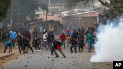 Protesters throw rocks at police during clashes next to a cloud of tear gas in the Kibera area of Nairobi, Kenya, July 19, 2023.