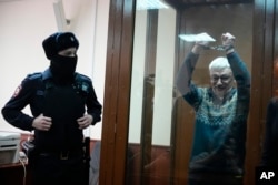 FILE – Oleg Orlov, co-chair of the human rights group Memorial, gestures from a defendants’ cage in court in Moscow, Russia, Feb. 27, 2024.
