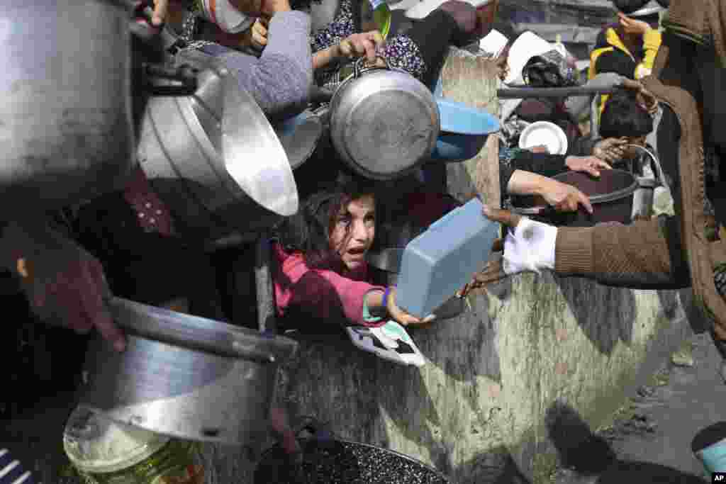 Palestinians line up for free food during the ongoing Israeli air and ground offensive on the Gaza Strip in Rafah.