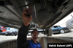 A worker sands an under a restored Cadillac Seville at restorer Khosro Dahaghin's workshop in Roudehen, some 30 miles (45 kilometers) east of downtown Tehran, Iran, Wednesday, June 7, 2023. (AP Photo/Vahid Salemi)