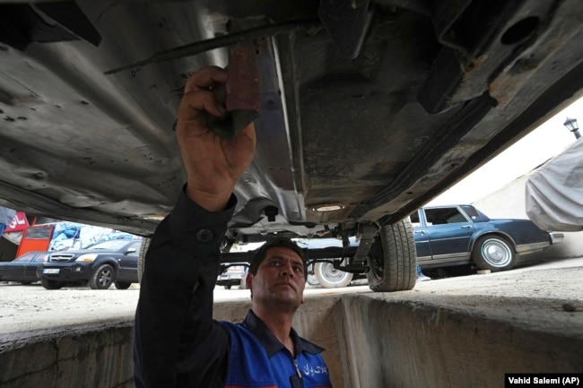 A worker sands an under a restored Cadillac Seville at restorer Khosro Dahaghin's workshop in Roudehen, some 30 miles (45 kilometers) east of downtown Tehran, Iran, Wednesday, June 7, 2023. (AP Photo/Vahid Salemi)