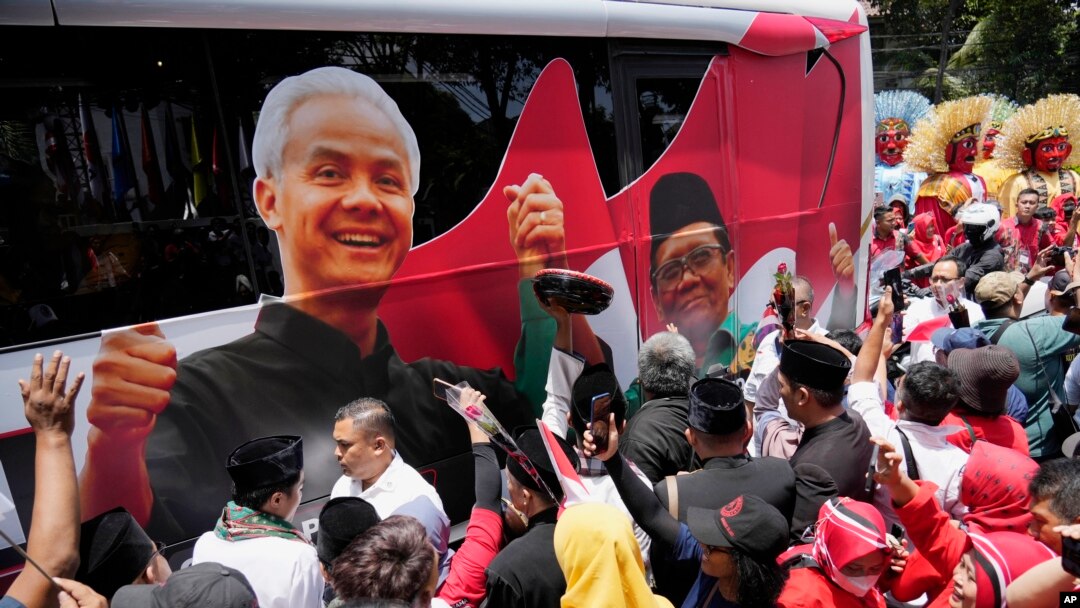 FILE - Para pendukung paslon capres-cawapres Pilpres 2024 Ganjar Pranowo dan Mohammad Mahfud, mengelilingi bus kampanye saat mendaftarkan diri di gedung Komisi Pemilihan Umum di Jakarta, 19 Oktober 2023. (AP/Achmad Ibrahim)