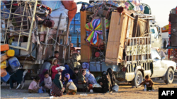 Afghan refugees, along with their belongings, sit beside the trucks at a registration center upon their arrival from Pakistan in Takhta Pul district of Kandahar province on Dec. 18, 2023.