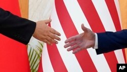 美國總統拜登與中國國家主席習近平在印度尼西亞巴釐島20國集團峰會期間舉行面對面會談前伸手握手。（2022年11月14日）