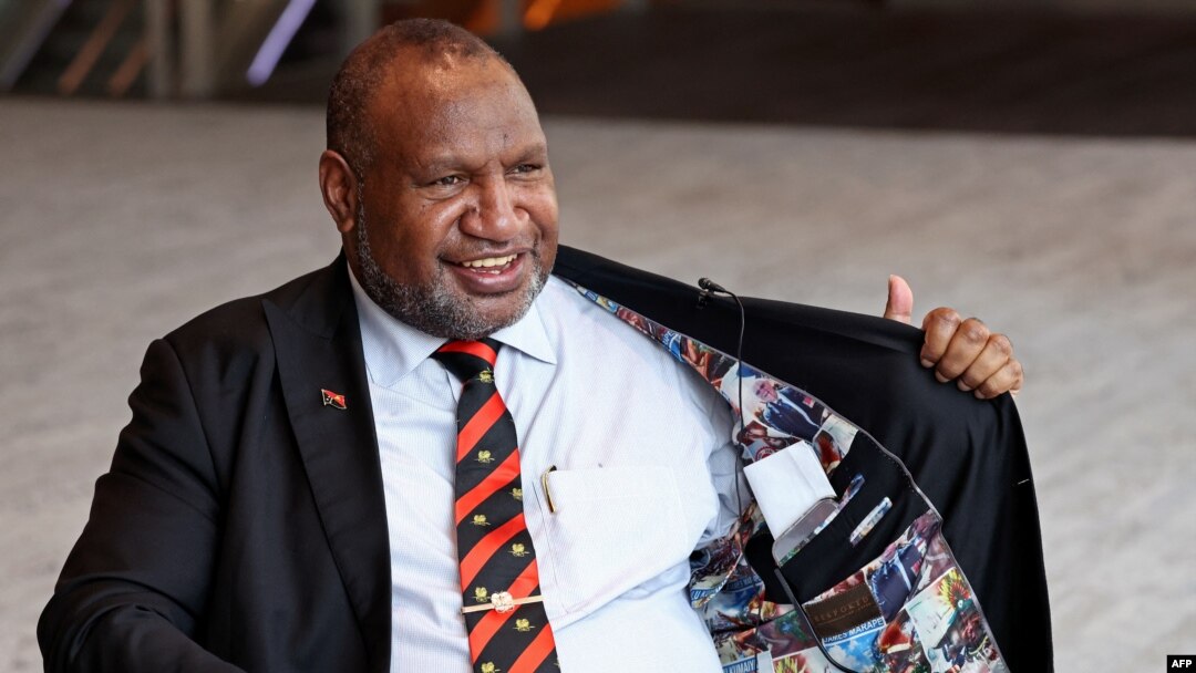 Perdana Menteri Papua Nugini James Marape memperlihatkan bagian dalam jaketnya yang dipenuhi foto-foto lama dirinya, saat wawancara di Sydney pada 11 Desember 2023. (DAVID GRAY / AFP)