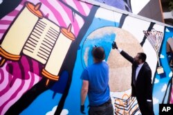 Rabbi Yehuda Teichtal (kanan), dan seniman grafiti Tobo, menyemprotkan cat pada dinding grafiti sebagai bagian dari Kampus Yahudi Pears yang baru di Berlin, Jerman, Senin, 12 Juni 2023. (AP/Markus Schreiber)