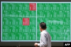 Seorang pria mengamati papan kutipan elektronik yang menampilkan harga saham Nikkei 225 di Bursa Efek Tokyo di Tokyo, 2 Agustus 2024. (Kazuhiro NOGI / AFP)