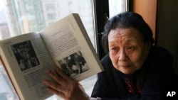 FILE - AIDS activist Gao Yaojie displays a book she wrote about AIDS in China, during an interview in Beijing, Feb. 22, 2007.