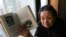 FILE - AIDS activist Gao Yaojie displays a book she wrote about AIDS in China, during an interview in Beijing, Feb. 22, 2007.