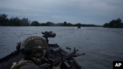 FILE - Ukrainian soldiers navigate on the Dnipro river by boat at the frontline near Kherson, Ukraine, Sunday, June 11, 2023.
