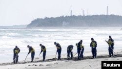 Polisi mencari petunjuk tentang orang hilang dari bencana gempa bumi dan tsunami tahun 2011 di pantai dekat PLTN Fukushima Daiichi yang lumpuh akibat tsunami di kota Namie, prefektur Fukushima, Jepang, 11 Maret 2024, pada peringatan 13 tahun bencana tersebut. (Kyodo via REUTERS)