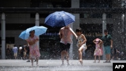 Children play as they cool off at a water fountain during a heat wave in Hong Kong on July 9, 2023.