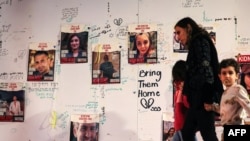 People walk in front of images of Israeli hostages held in Gaza since the Oct. 7 attack by Hamas militants in southern Israel during a protest to ask for their release in Tel Aviv on Nov. 22, 2023.