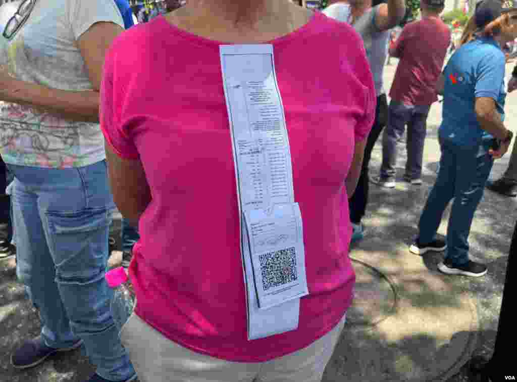 Una mujer se cualga una réplica de un acta alectoral que da el triunfo a la oposición en los comicios presidenciales. Visto en una protesta en Caracas, Venezuela, el 17 de agosto de 2024 [Fotos, VOA].