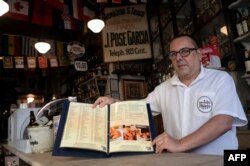 Carlos Fionda (59), manajer bar Armazem Sao Thiago di Lapa di Rio de Janeiro, Brazil, menunjukkan menu mereka, 24 Mei 2023. (MAURO PIMENTEL/AFP)