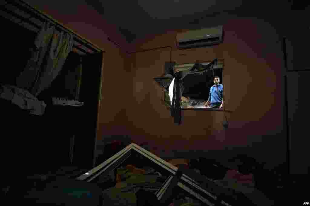 A Palestinian is seen from the window of a damaged house in a refugee camp in Tulkarm, where the Israeli army carried out overnight raids, in the occupied West Bank.