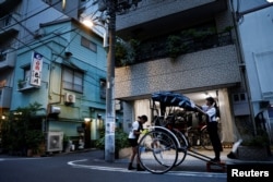 Drivers Akina Suzuki (left), 19, and Misato Otoshi, 30, clean up their rickshaw after work at a garage in the Asakusa district, Tokyo, Aug. 17, 2023.