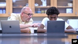 History teacher Matt Brophy works with Flerentin “Flex” Jean-Baptiste, 16, of Medford, Mass., on making up late assignments during summer school at Medford High School, Friday, Aug. 2, 2024.