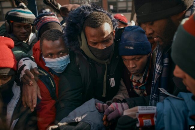 Migrants pick up clothes as mutual aid groups distribute food and clothes under cold weather near the Migrant Assistance Center at St. Brigid Elementary School, Jan. 20, 2024, in New York.