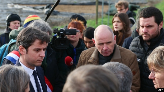 French Prime Minister Gabriel Attal (L) speaks with farmers as he arrives for a visit at a farm in Parcay-Meslay, near Tours, on Jan. 28, 2024, amid nationwide protests called by several farmers unions on pay, tax and regulations.