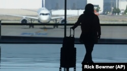 FILE - A holiday traveler looks out at a airplane at Salt Lake City International Airport, in Salt Lake City, July 3, 2024. (AP Photo/Rick Bowmer, File)
