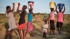 FILE - Residents of Pumula East township walk home after fetching water from a well, as temperatures soar during an El Nino-related heatwave and drought affecting a large part of the country, in Bulawayo, Zimbabwe March 7, 2024.