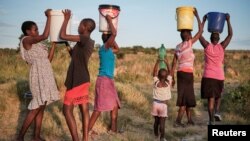 FILE - Residents of Pumula East township walk home after fetching water from a well, as temperatures soar during an El Nino-related heatwave and drought affecting a large part of the country, in Bulawayo, Zimbabwe March 7, 2024.