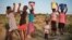 FILE - Residents of Pumula East township walk home after fetching water from a well, as temperatures soar during an El Nino-related heatwave and drought affecting a large part of the country, in Bulawayo, Zimbabwe March 7, 2024.