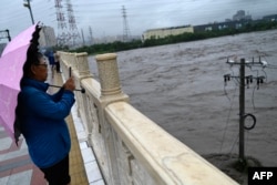A man stands by the overflooded Yongding river, after heavy rains in Mentougou district in Beijing on July 31, 2023.