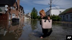 A local resident makes her way through a flooded road after the Kakhovka dam collapsed, in Kherson region, Ukraine, Jun 6, 2023.