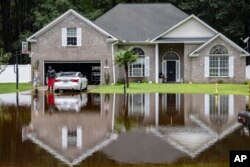 Keon Johnson and his wife Zyla Johnson, left, talk about how to get to work since his house on Tappan Zee Drive that was flooded on Monday from Tropical Storm Debby, in Pooler, Georgia, Aug. 7, 2024.